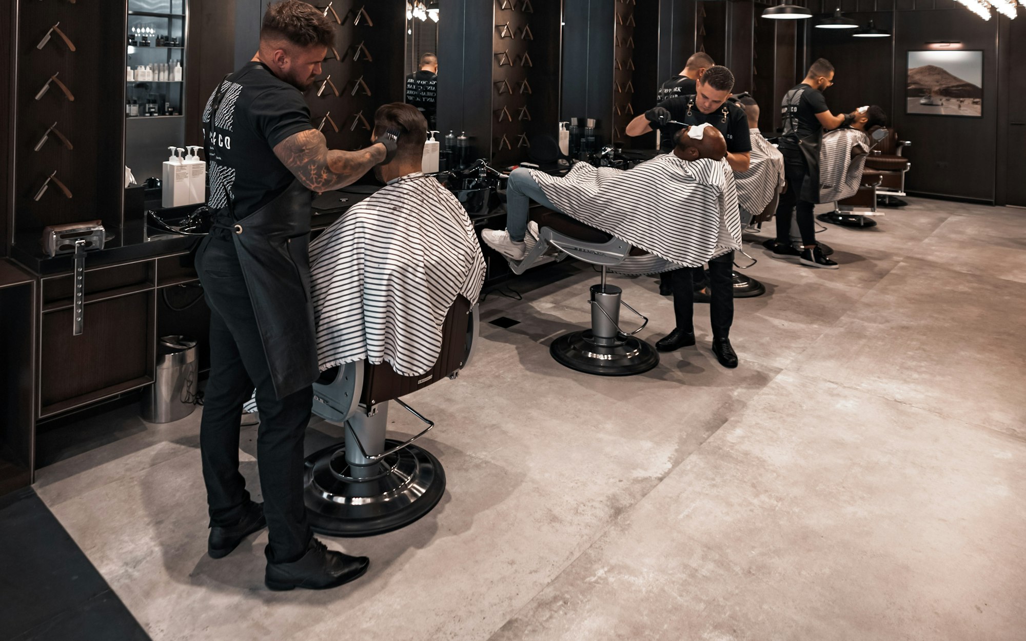Inside the shop: barbers working at their chairs under warm light